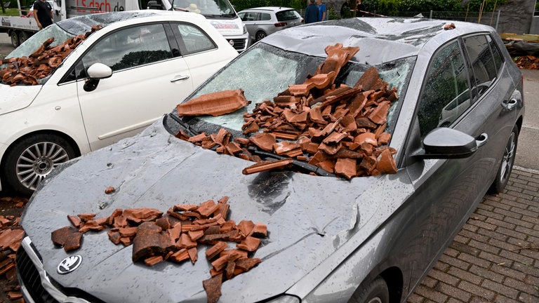 Das Dach ist abgedeckt, herabstürzende Ziegel haben auch parkende Autos demoliert.