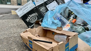 Müll wie Kartons und alte Becher auf einem Gehweg. Mögliche Überreste der Partynacht und des Nabadas am Schwörmontag in Ulm.