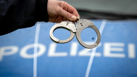 Handschellen vor einem Polizeiwagen