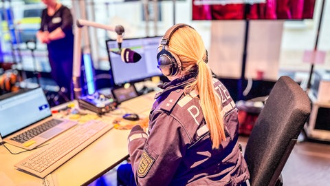 Eine Polizistin sitzt am Nachrichtenplatz im PopUp Studio.