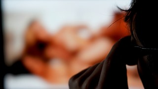 Ein User sieht einen Porno auf einem Bildschirm. Unbekannte haben bei der Volkshochschule Ulm Pornos eingespielt und rechte Parolen verbreitet.