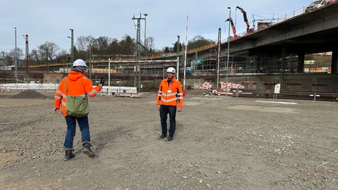 B10 Projektleiter Gerhard Fraidel der Stadt Ulm nimmt ein Social Media Video auf. Er steht auf dem Boden, der extra für den riesigen Kran aufbereitet wurde. 
