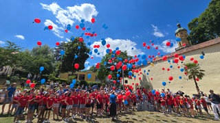 Kinder lassen blaue und rote Luftballons steigen: Beim Rutenfest 2025 war der Himmel zwar auch blau, aber die Hitze nicht gar so heftig.