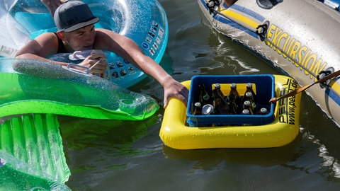 Ein Bierkasten ist zur Kühlung beim Nabada in der Donau zwischen zwei Booten. Aus Flaschen trinken ist okay, nur wer das Donauwasser schluckt, riskiert eine Magen-Darm-Erkrankung.