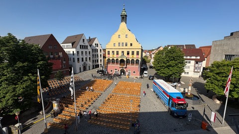 Holzstühle vor einem Haus mit Balkon: Die Schwörfeier in Ulm findet auf dem Weinhof statt, vom Balkon des Schwörhauses aus spricht der OB