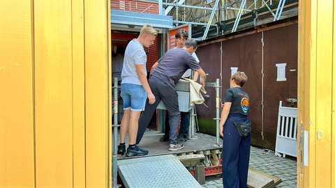 Mehrere Händler beladen den Lastenaufzug für den Wochenmarkt auf dem Turm des Ulmer Münsters.