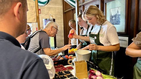 Markthändlerin Laura Glöckler wiegt Äpfel, eine andere präsentiert Zitronen. Auf dem Wochenmarkt in der Turmhalle des Ulmer Münsters gibt es vieles, was es auch auf dem regulären Wochenmarkt gibt. 
