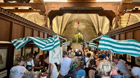 Viele Menschen tummeln sich zwischen den Ständen des Ulmer Wochenmarkts in der Turmhalle des Münsterturms. Elf Händler beteiligen sich am Wochenmarkt im Turm des Ulmer Münsters.