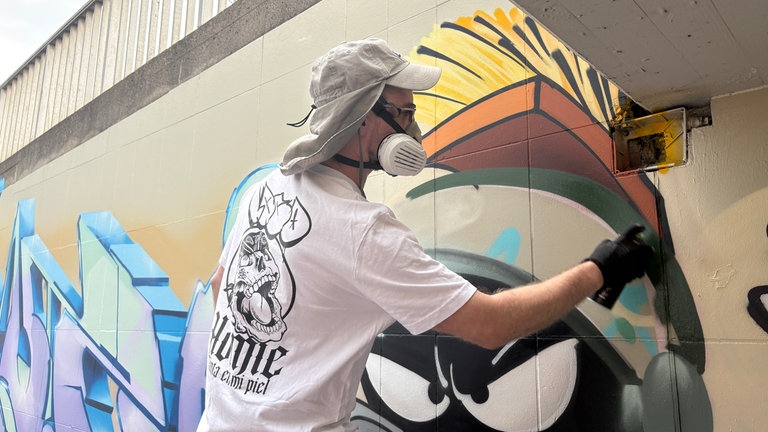Graffiti Künstler Milo sprüht ein Graffiti in einer Ulmer Unterführung 