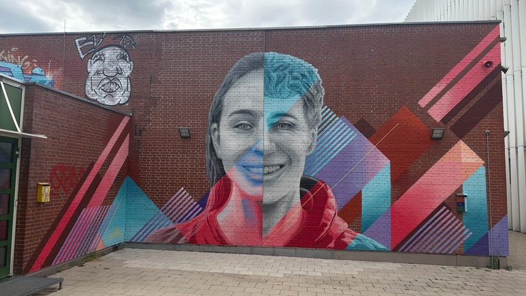 Graffiti Kunst des Ulmer Künstlers Milo. Ein Gesicht zur Hälfte Junge zur andern Mädchen auf der Fassade einer Ulmer Schule. 