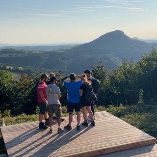 Die Wandergruppe Wandersocken steht auf einer Aussichtsplattform und schaut in die Ferne. Beim gemeinsamen Wandern werden aus Fremden oft Freunde.