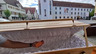 Ein Handy wird in einen Sarg gelegt. Das ist Teil einer Ausstellung in der Johanniskirche in Schwäbisch Gmünd. Es geht dabei auch um Digital Detox.