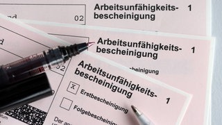 Stifte liegen auf den Arbeitsunfähigkeitsbescheinigungen für Arbeitnehmer im Falle einer Krankschreibung durch den Arzt.