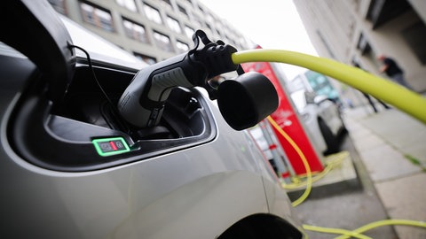 Zwei E-Autos stehen an Ladesäulen in der Innenstadt