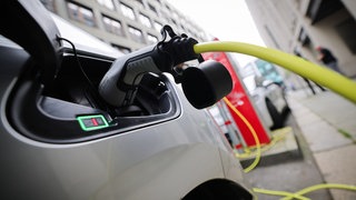 Zwei E-Autos stehen an Ladesäulen in der Innenstadt