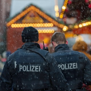 Zwei Polizisten gehen Streife auf einem Weihnachtsmarkt. In diesem Jahr muss auch ein generelles Messerverbot kontrolliert werden.