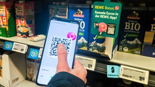 App auf dem Handy scannt Ware im Supermarktregal