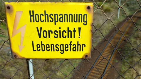 Hochspannungsschild über den Gleisen