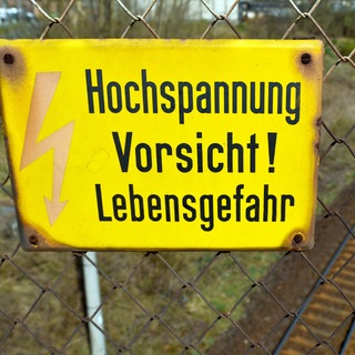 Hochspannungsschild über den Gleisen