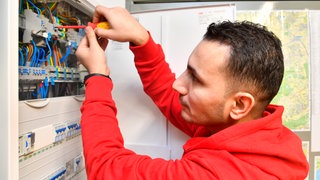 Syrer und Syrerinnen arbeiten als Elektriker (wie auf dem Foto) oder anderen Berufen mit Fachkräftemangel.