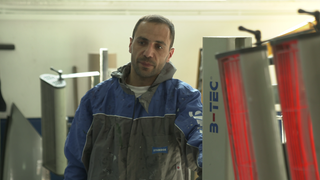 Der Geflüchtete Armenier Kirakosyan in einem Schutzanzug in einem Karosseriebau, wo er eine Ausbildung macht.