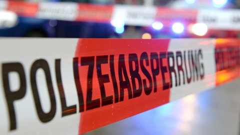 Ein Band mit der Aufschrift "Polizeiabsperrung" ist an einem Unfallort befestigt.