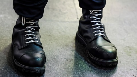 Ein Teilnehmer einer rechtsextremen Kundgebung trägt schwarze Springerstiefel mit weißen Schnürriemen, ein weit verbreitetes Symbol der rechten Szene.
