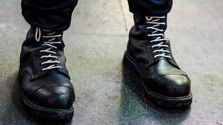 Ein Teilnehmer einer rechtsextremen Kundgebung trägt schwarze Springerstiefel mit weißen Schnürriemen, ein weit verbreitetes Symbol der rechten Szene.