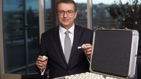 Jürgen Häfner, Geschäftsführer von Lotto RLP, hält Lotto-Kugeln hoch.