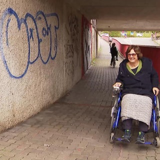 Eine Frau im Rollstuhl durchfährt eine Unterführung