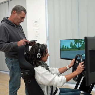 Fahrlehrer Alex Stein steht neben einem Fahrsimulator. Die Reform der Führerscheinprüfung sieht vor, dass Simulatoren für Fahrtrainings eingesetzt werden dürfen.