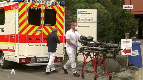 Sanitäter vor einem Rettungswagen mit einer Krankenliege
