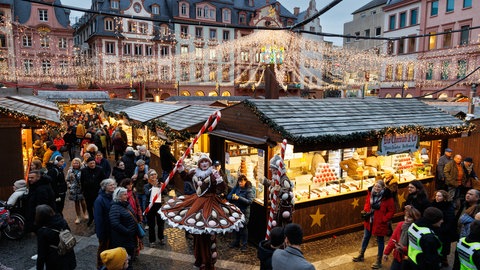 Auf dem Mainzer Weihnachtsmarkt warten unter dem mit Lichterketten erhellten Marktplatz immer wieder kleine - oder auch große Überraschungen. Wie zum Beispiel diese Lebkuchen-Stelzenläufer.