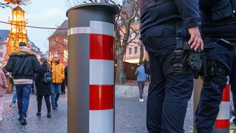 Sicherheitspersonal steht an einem Lkw-Poller in Mainz (Archivbild). Auch in diesem Jahr gibt es zusätzliche Polizisten auf dem Weihnachtsmarkt.