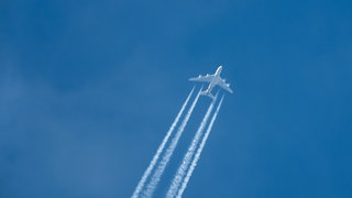 Ein Airbus zieht bei blauem Himmel Kondensstreifen hinter sich her.