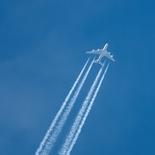 Ein Airbus zieht bei blauem Himmel Kondensstreifen hinter sich her.