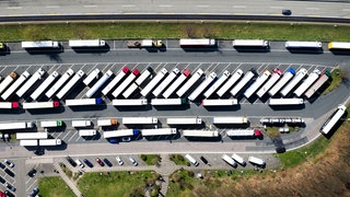 Drohnenbild - Lkw stehen auf einem Rastplatz. Es fehlen tausende Parkplätze, auf denen Fahrer:innen ihre Ruhezeiten einhalten können.