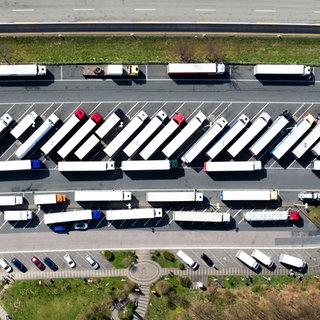 Drohnenbild - Lkw stehen auf einem Rastplatz. Es fehlen tausende Parkplätze, auf denen Fahrer:innen ihre Ruhezeiten einhalten können.