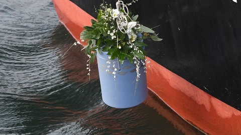 Eine Urne zur Flussbestattung wird ins Wasser gelassen. 