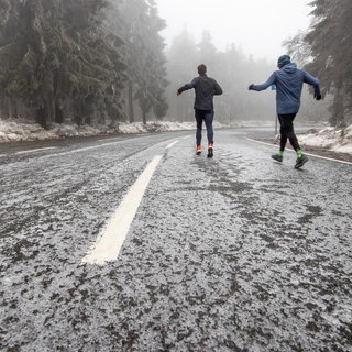 Zwei Fußgänger schliddern über eine Landstraße nach Eisregen (Archivbild).