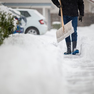 Ein Mann schippt und räumt Schnee weg - wer in RLP der Räumpflicht nicht nachkommt, dem droht ein Bußgeld.