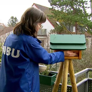 Eine Frau füllt Vogelfutter in ein Vogelhäuschen