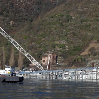 Kräne halten den Rumpf des bei St. Goarshausen auf dem Rhein gekenterten Säuretankers Waldhof. Die Havarie war eines der größten Schiffsunglücke, die Rheinland-Pfalz bislang erlebt hat.