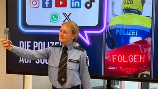 Influencerin Laila Ziegler macht ein Selfie vor einem Social-Media-Werbebanner der Polizei Rheinland-Pfalz