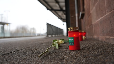 Trauerkerzen und Blumen an einem Bahnsteig. Nach dem tödlichen Angriff auf einen Zugbegleiter im rheinland-pfälzischen Landstuhl will die Staatsanwaltschaft heute über das weitere Vorgehen berichten. Gegen den Täter liegt ein Haftbefehl vor.