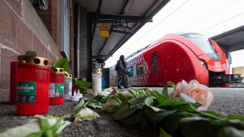 Kerzen und Blumen erinnern auf dem Bahnsteig am Bahnhof in Landstuhl an den getöteten Bahnmitarbeiter Serkan C. Der mutmaßliche Täter war offenbar bereits vor der Tat auffällig geworden.
