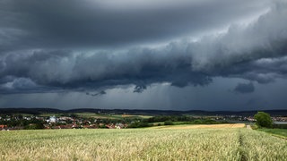 Gewitterwolken schweben drohend über einem Feld. Am Wochenende müssen sich die Menschen in Rheinland-Pfalz auf Gewitter und Starkregen einstellen.