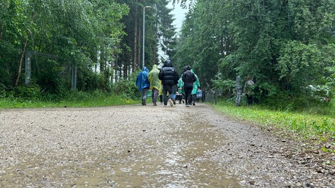 Rock am Ring-Fans laufen auf matschigem Weg durch den Regen