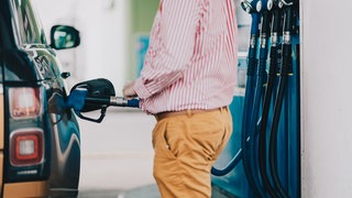 Ein Mann steht an der Zapfsäule einer Tankstelle. Das Tanken in Rheinland-Pfalz ist sehr teuer, besonders an Autobahn-Tankstellen. Das ergab eine Auswertung (Symbolbild).