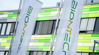 Die Flaggen des Pharma-Unternehmens Biontech flattern vor der Firmenzentrale im Wind.